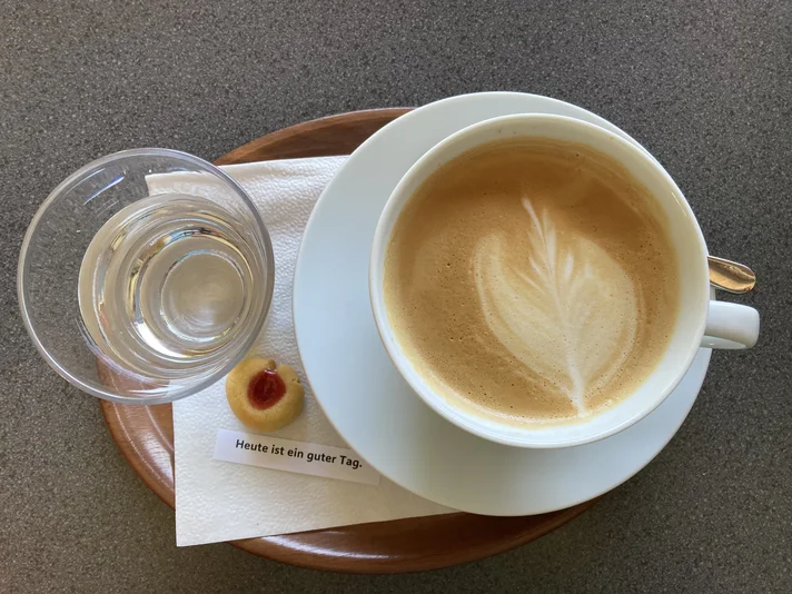 Kaffeetasse mit Cappuccino, Wasserglas und Teegebäck